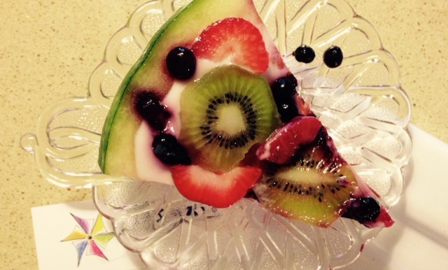 A slice of fruit pizza with kiwi, strawberry and blueberry.