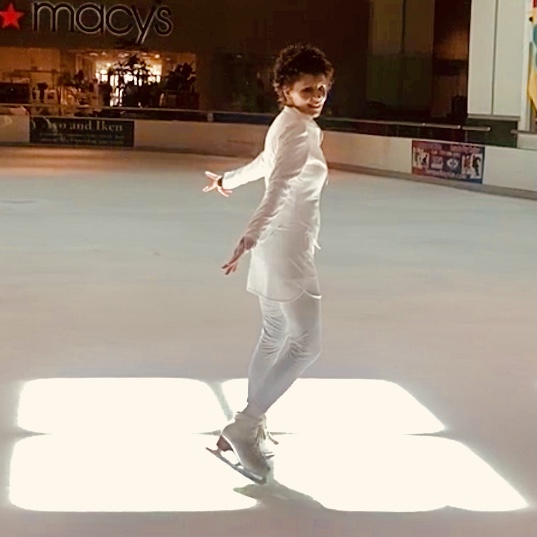 A person on a skateboard in the middle of an indoor rink.