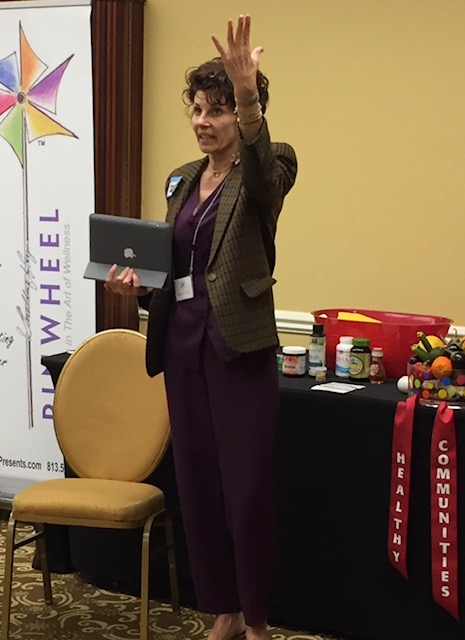 A woman in purple dress holding up an ipad.