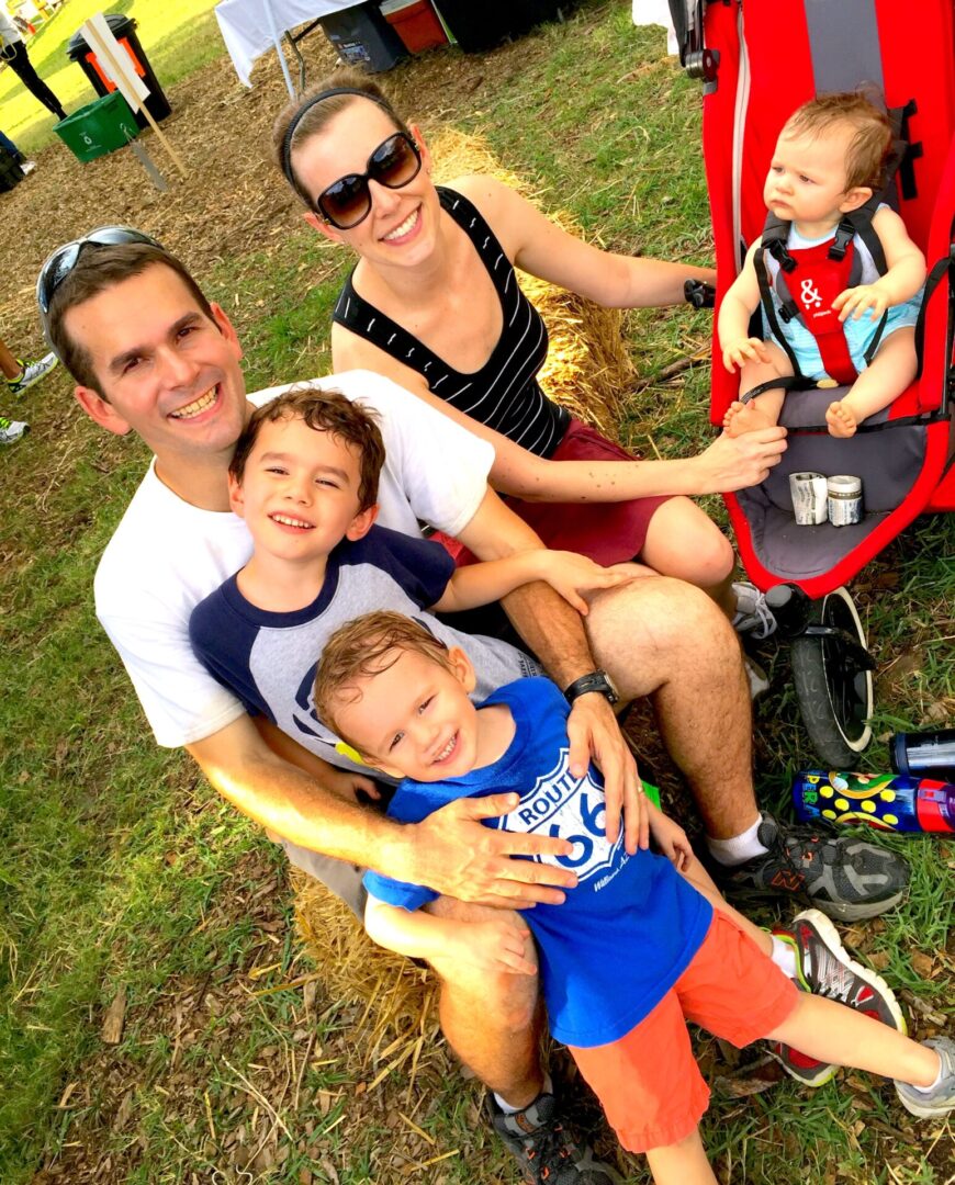 A family of five sitting on the grass.