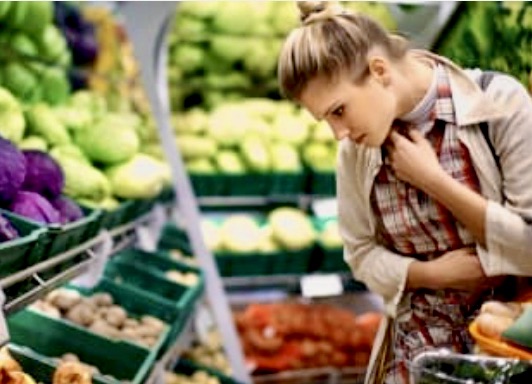 A woman in an apron is looking at produce.